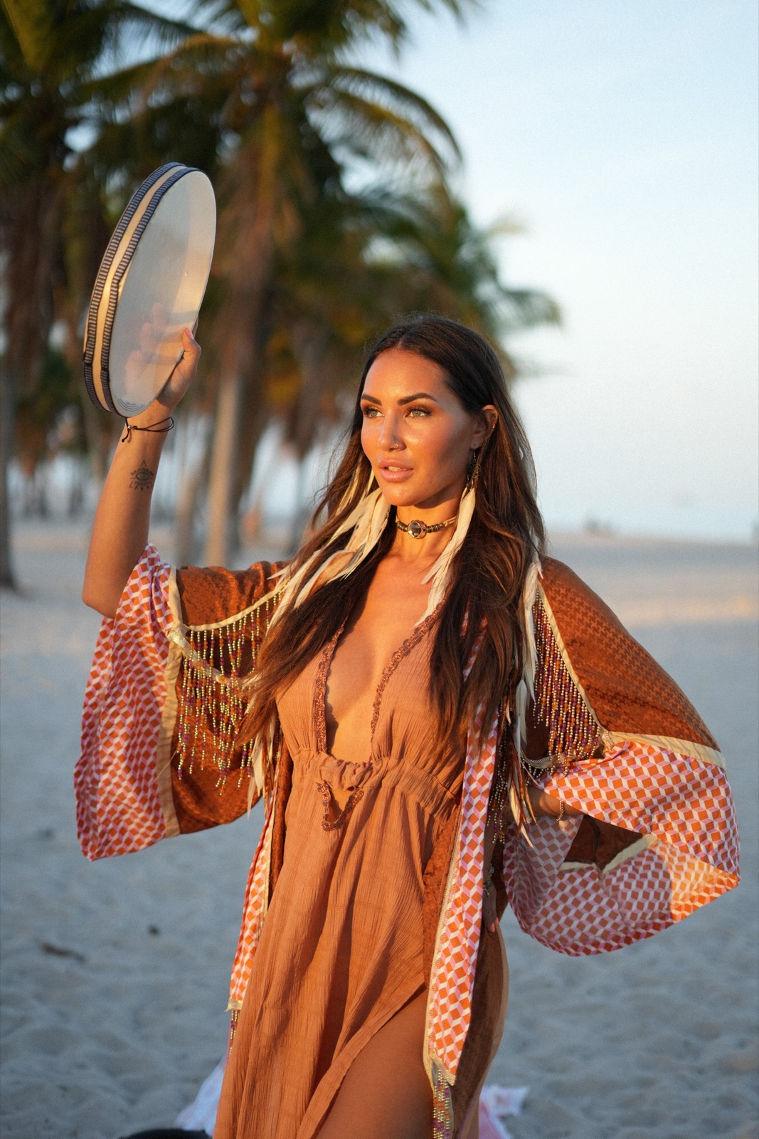 Linnebel playing a frame drum on the beach at sunset